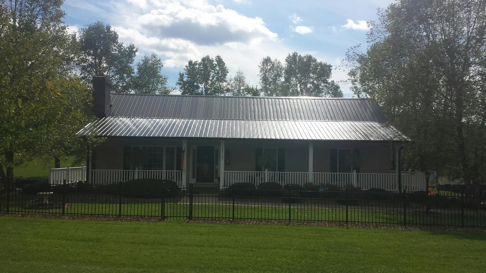 Gray metal roof on a brick ranch with a full width front porch — Gutter Guard Installation work by our crew in Addison